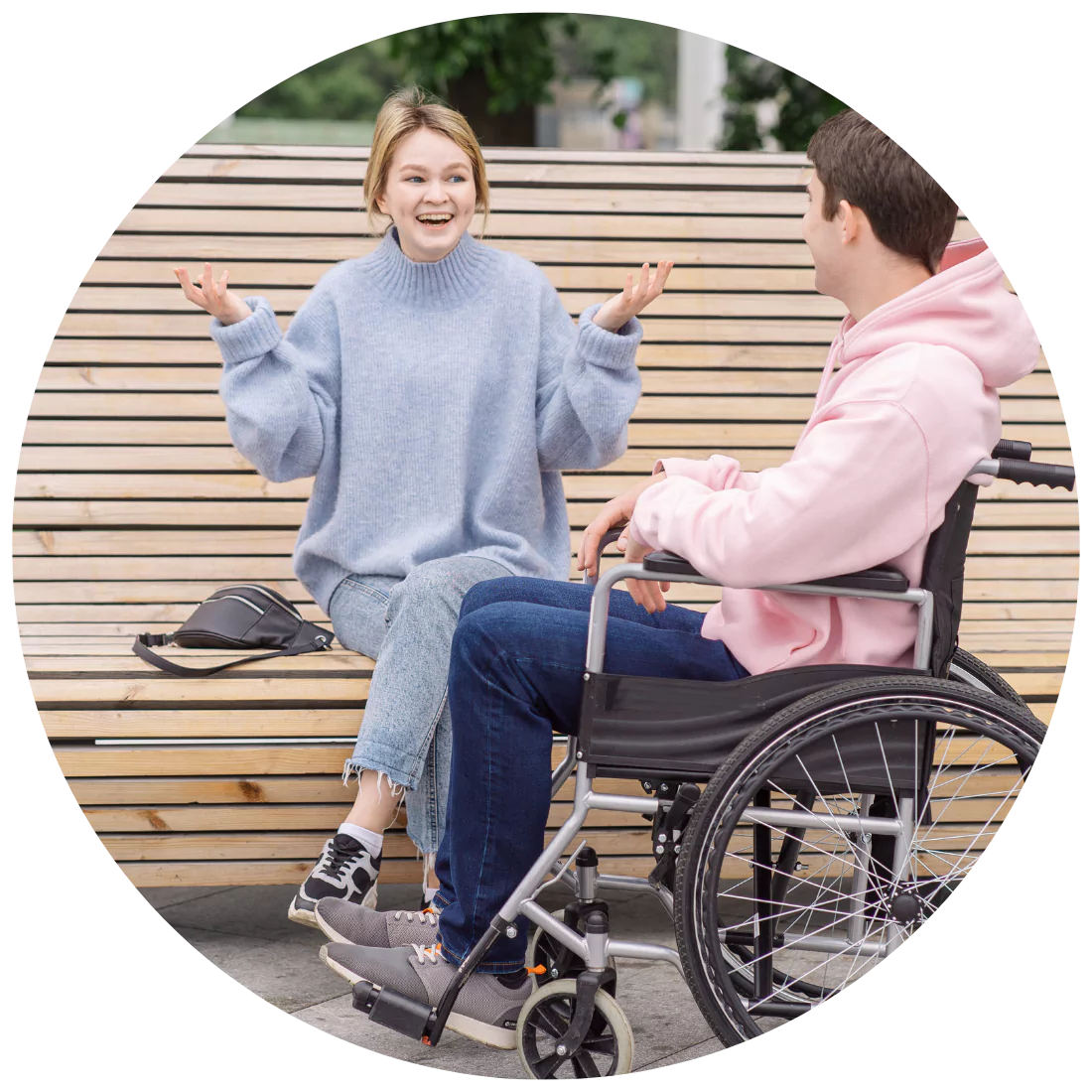 Disabled man sitting on his wheel chair and his support worker smiling while talking in the park